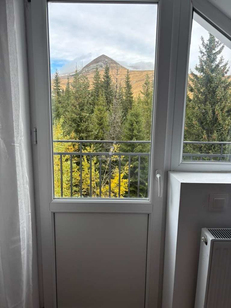 Balcony door open to the firs and the mountain peak