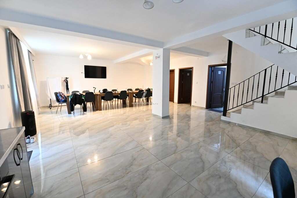 Living room with a long table, glossy tiles and stairs to the upper floor